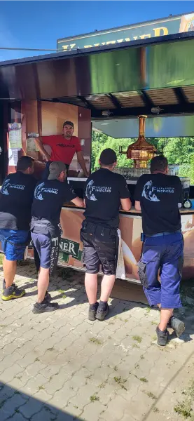 Gemeinschaft beim Fischfest, mehrere Vereinsmitglieder stehen gut gelaunt an einem Tisch
